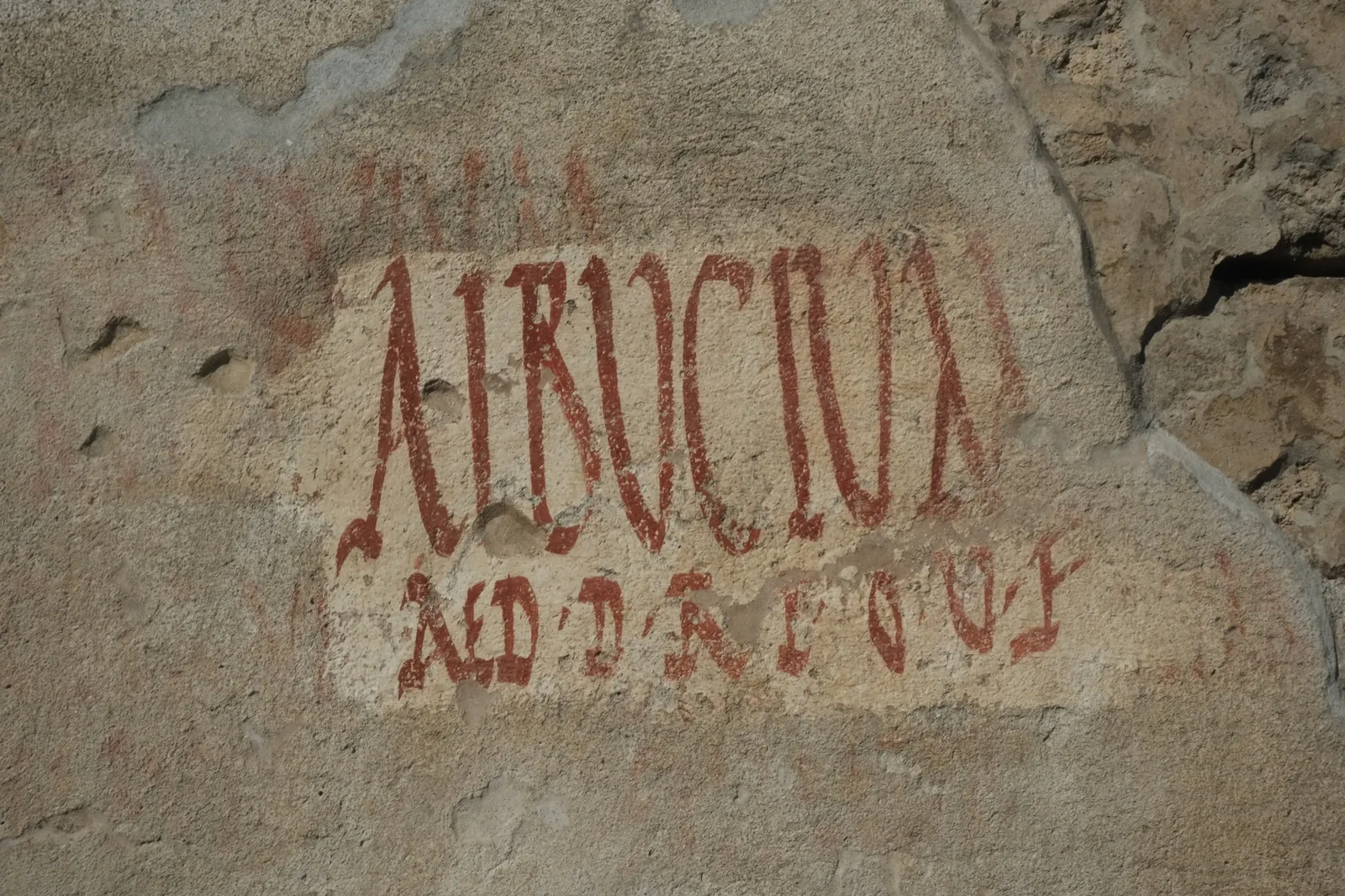 Tall red painted inscription on a Pompeii wall
